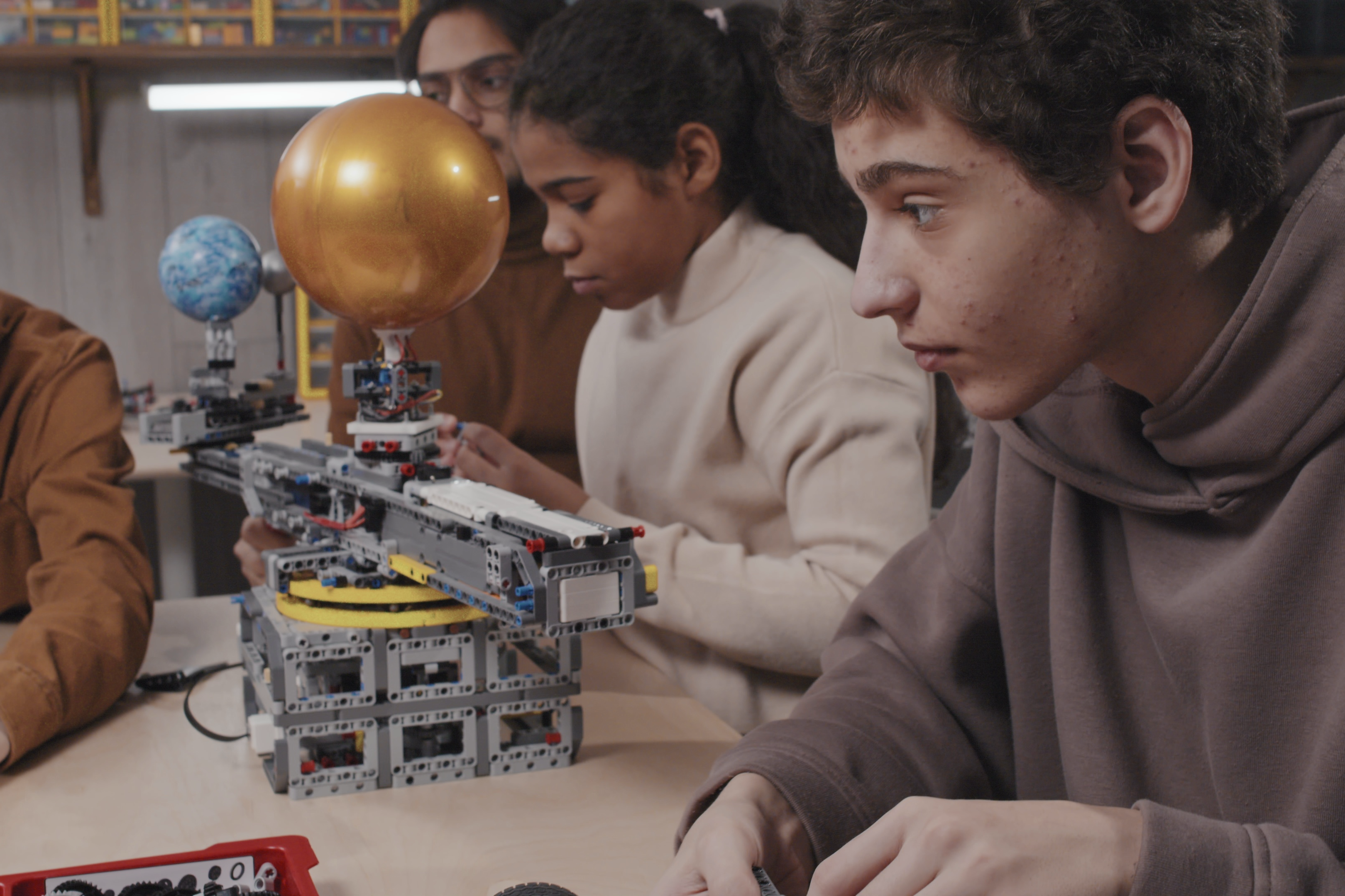 teen-boy-and-his-classmates-attending-modern-robotics-class-at-school-working-on-their-SBI-351521126